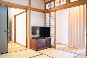 a living room with a flat screen tv in a room with windows at Umibe no yado yo-riyo-ri in Amami