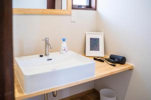 a bathroom with a white sink on a wooden counter at Umibe no yado yo-riyo-ri in Amami