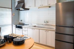 a kitchen with a table and a stainless steel refrigerator at Umibe no yado yo-riyo-ri in Amami +22 photos