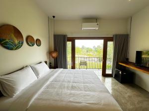 a bedroom with a large white bed and a balcony at Glai boutique hotel in Ban Cha Prong