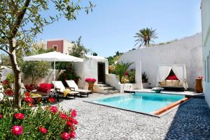 podwórko z basenem, stołem i krzesłami w obiekcie Santorini Heritage Villas w mieście Megalochori