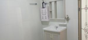 a white bathroom with a sink and a mirror at water fall resort soksan in Phumĭ Kaôh Rŏng