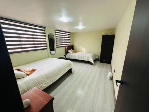 a small bedroom with two beds and a window at BaseCotopaxi Mini depart 5p free parking in Latacunga