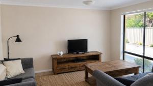 a living room with a tv and a couch and a table at Beachside on Kent in Busselton