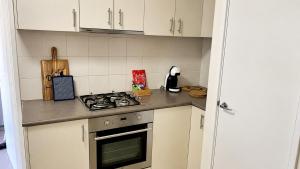 a kitchen with white cabinets and a stove top oven at Beachside on Kent in Busselton