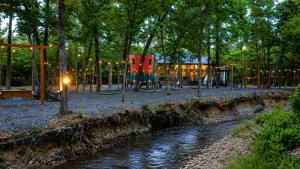 a playground in a park with a river and trees at Creek,Pool,Playhouse celebration estate, sleeps 21 in Broken Bow