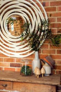 a mirror on a brick wall with a shelf with a vase at Edgewater on Quindalup Beachfront in Quindalup