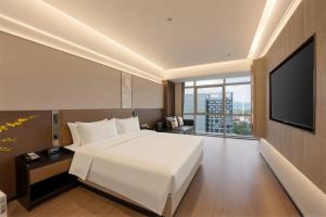 a bedroom with a white bed and a flat screen tv at 义乌雅寓酒店国际商贸城六区店 in Yiwu +33 photos
