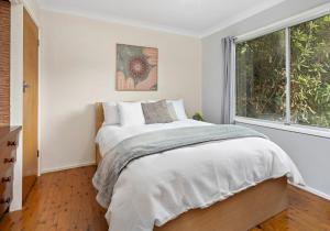 a white bedroom with a bed and a window at Tabone on Jones in Kiama Downs