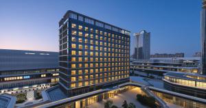 a rendering of a tall building with lights on at 义乌雅寓酒店国际商贸城六区店 in Yiwu