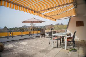 a patio with a table and chairs and an umbrella at Ihre exklusive Auszeit im Allgäu in Scheidegg