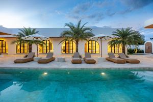 a resort with a pool with lounge chairs and umbrellas at DESAULU VILLAS - Boutique Private Room Pool View in Uluwatu