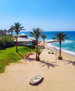 łódź na plaży z domem i palmami w obiekcie JHotelResorts w mieście Ad-Damur