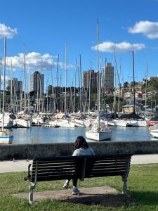a woman sitting on a bench looking at boats at Edgecliff Lodge Motel in Sydney