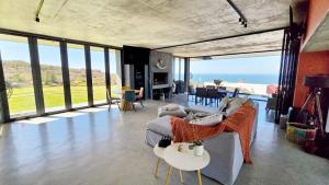 a living room with a couch and tables and windows at Walvishaai in Stompneusbaai