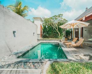 a swimming pool with a table and an umbrella at Jero Kelodan Villa in Tabanan +166 photos