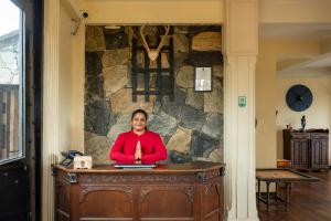a woman sitting at a desk with a laptop at Fort WindShire in Nuwara Eliya