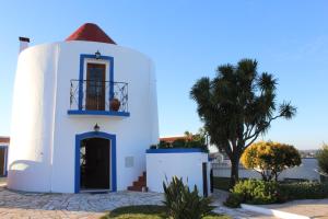 a white building with a balcony and a palm tree at Windmill Hill in Cercal
