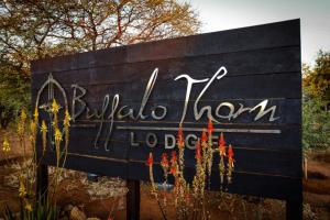 um sinal para um museu da vida selvagem com flores nele em Buffalo Thorn Lodge em Pilanesberg