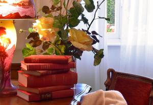 a stack of books on a table with a vase of yellow roses at Hostellerie de la Motte jean in Saint-Coulomb