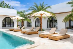 a pool with chaise lounge chairs and umbrellas at DESAULU VILLAS - Boutique Private Room Pool View in Uluwatu