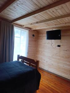 a bedroom with a bed and a flat screen tv at Hotel Páramo de Sumapaz in San Juan