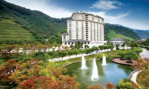 a building with water fountains in front of a lake at Elysian Gangchon Resort in Chuncheon