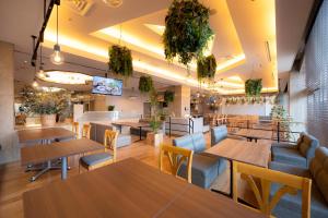 a restaurant with tables and chairs and plants at Meitetsu Komaki Hotel in Komaki