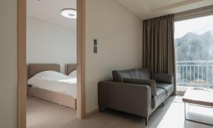 a bedroom with a bed and a chair and a window at Elysian Gangchon Resort in Chuncheon +18 photos