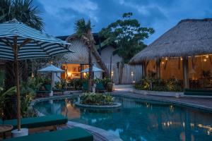 a resort pool with chairs and umbrellas at night at Hotel Together Bali in Uluwatu