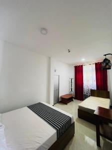 a bedroom with two beds and a desk and red curtains at Veenu Homestay in Badulla