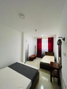 a bedroom with two beds and red curtains at Veenu Homestay in Badulla