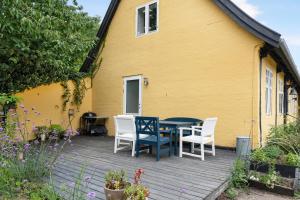 a yellow house with a table and chairs on a deck at Holiday Apartment On Bornholm With Sea View in Svaneke