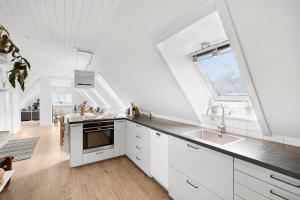 a kitchen with white cabinets and a large window at Holiday Apartment On Bornholm With Sea View in Svaneke +13 photos