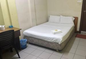 a bed in a small room with a desk and a bed sidx sidx at White House Hotel Kluang in Kluang