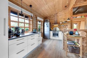 a kitchen with white cabinets and a wooden ceiling at Charming Cabin With Wilderness Hot Tub in Asnæs