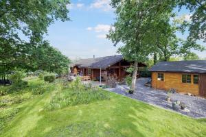 a log cabin with a garden in front of it at Charming Cabin With Wilderness Hot Tub in Asnæs