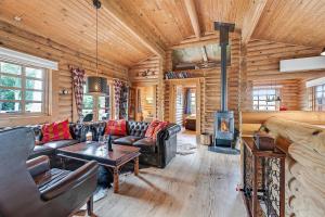 a living room with leather furniture in a log cabin at Charming Cabin With Wilderness Hot Tub in Asnæs