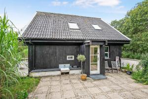 a small black house with a potted plant in front of it at Lovely Beach Home Enveloped In Green Surroundings in Ebeltoft