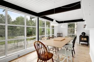 a dining room with a table and chairs and windows at Lovely Beach Home Enveloped In Green Surroundings in Ebeltoft +22 photos