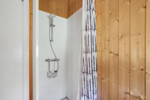 eine Dusche in einem Raum mit einer Holzwand in der Unterkunft Schönes Sommerhaus Mit Herrlichem Blick in Ølsted + 17 Fotos