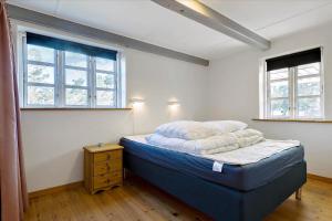 a bedroom with a bed in a room with two windows at Holiday Apartment In Peaceful Surroundings in Neksø
