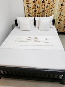 a bed with white sheets and two shoes on it at Shalom View Homestay in Kandy