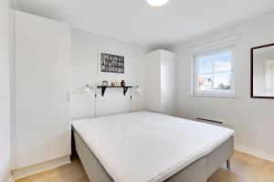 a white bedroom with a large bed in it at Charming Terraced House By The Beach And Forest in Bro