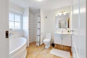 a bathroom with a tub and a toilet and a sink at Charming Terraced House By The Beach And Forest in Bro +32 photos