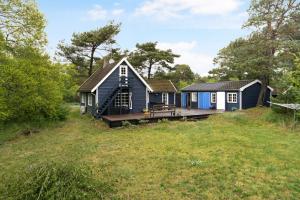 a tiny house with a deck in a field at Charming Cottage Near The Beach in Neksø