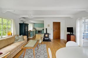 a living room with a couch and a stove at Charming Cottage Near The Beach in Neksø