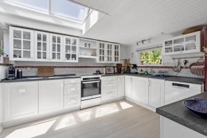 a white kitchen with white cabinets and a window at Unique Holiday Home In Quiet Surroundings in Storvorde +17 photos