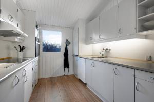 a kitchen with white cabinets and a window at Cozy Summer House On Scenic Djursland in Glesborg +16 photos