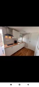 a large kitchen with white cabinets and wood floors at chalecito con piscina y barbacoa in Benicarló